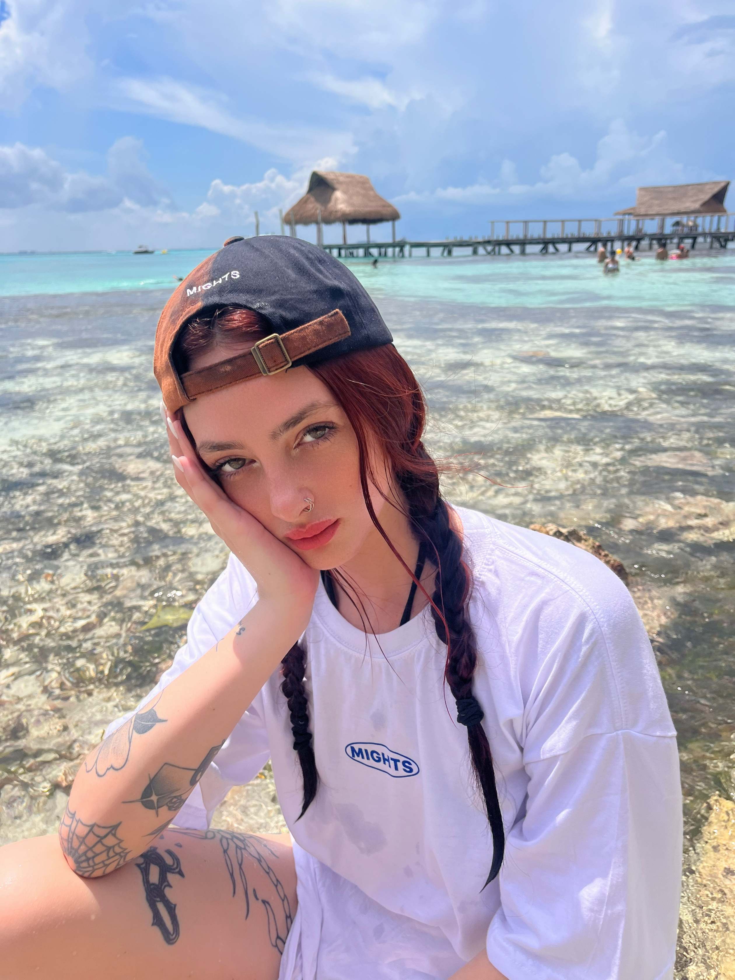 Luna at a turquoise beach in a backwards cap and oversized white tee